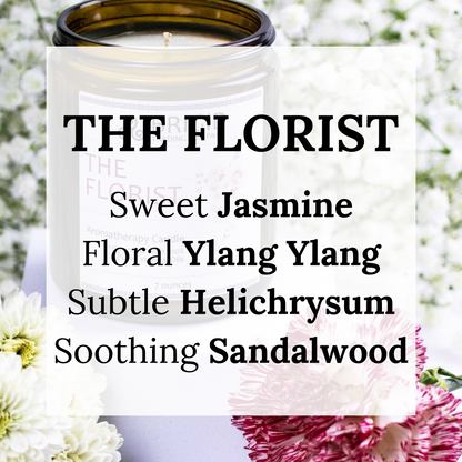 the florist premium aromatherapy grade essential oil candle candles by brigid trading company washington state united states ireland seven ounces kitsap therapy therapeutic benefits natural health white babys breath background with white flowers and pink flowers in the foreground candle in center