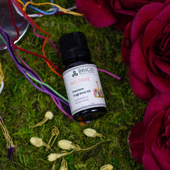 beltane diffuser oil rose jasmine clary sage and frankincense hand made natural celtic inspired made in kitsap county washington state image shows a moss background with a red flower and jasmine flowers with maypole and bottle of diffuser essential oil blended fragrance in amber glass bottle