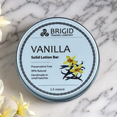 vanilla solid lotion bar by brigid trading company on a marble countertop with vanilla flowers in the frame