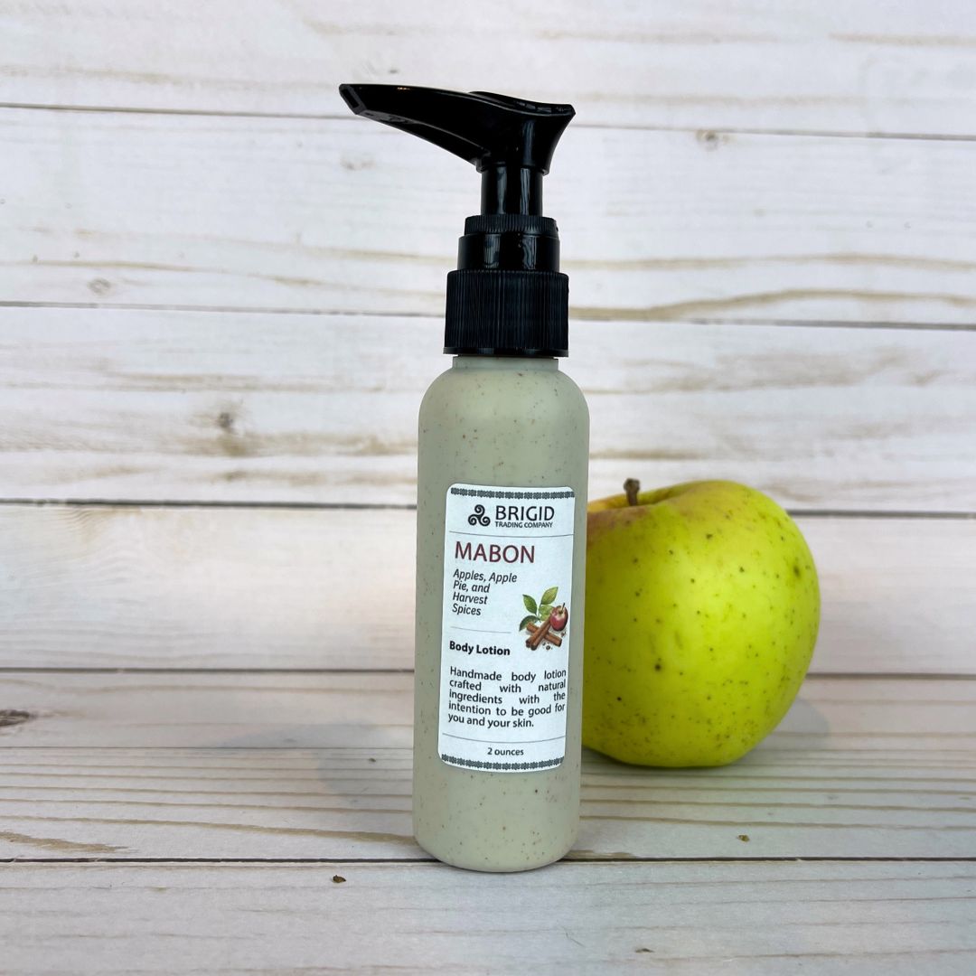 mabon body lotion 2 ounce two in eco pump bottles wheat straw black tops natural hand mixed harvest moon festival gifts for mom girlfriend pagan christian catholic presents for fall autumn apples apple cinnamon apple pie scented fresh apples harvest spices image of bottles on wooden backdrop with fresh green and red apple