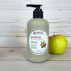 mabon body lotion 8 ounce eight in eco pump bottles wheat straw black tops natural hand mixed harvest moon festival gifts for mom girlfriend pagan christian catholic presents for fall autumn apples apple cinnamon apple pie scented fresh apples harvest spices image of bottles on wooden backdrop with fresh green and red apple