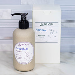 original body lotion by brigid trading company unscented fragrance free sensitive skin skincare all natural organic hand made in washington state dye free scent free nonscented goat's milk shea butter lotion body lotion self care package original studio photography by brigid trading company bremerton washington state white tile countertop image with product photographs shown with gift box and bathroom countertop scene