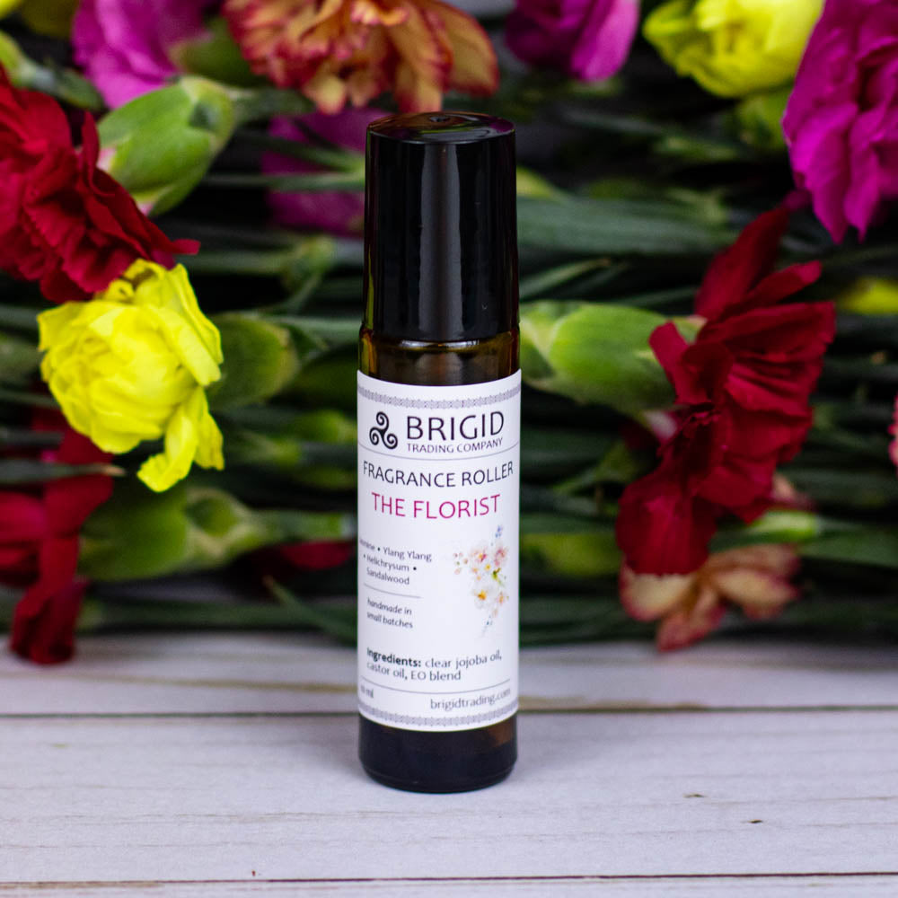 fragrance roller oil scent roller perfume bottle by brigid trading company llc jasmine ylang ylang sandalwood helichrysum jojoba oil, castor oil, essential oils only aromatherapy clean ingredients amber bottles with flowers in the background the florist 