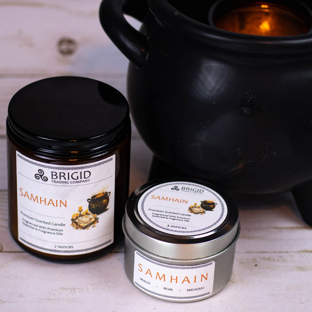 samhain premium soy wax candle celtic spirituality premium scented candles from brigid trading company llc dragons blood resin merlot spices patchouli scent candles large and small handmade in washington state kitsap county cauldron in background two sized candles one in glass jar one in metal tin