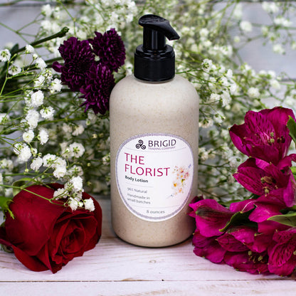 the florist body lotion 8 ounce bottle in wheat straw package shown with babys breath rose pink and purple flowers natural lotion by brigid trading company llc kitsap county washington state original photography by kelly nelson of brigid trading company 2024 copyright protected