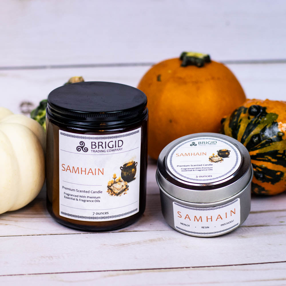 samhain premium soy wax candle celtic spirituality premium scented candles from brigid trading company llc dragons blood resin merlot spices patchouli scent candles large and small handmade in washington state kitsap county pumpkins and gourds in background with two sized candles one in glass jar one in silver metal tin