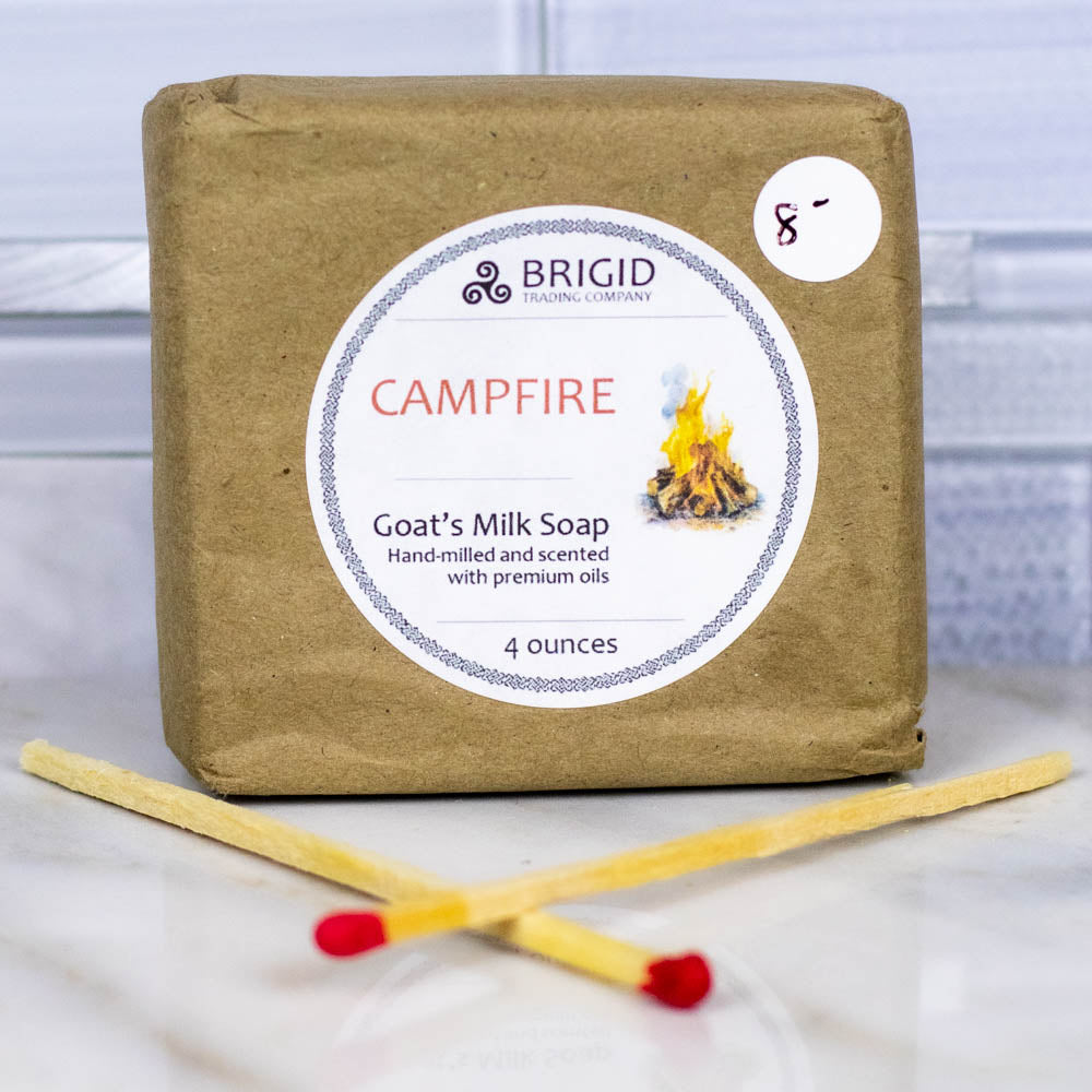 goats milk soap natural by brigid trading company campfire scent hand milled mesquite cedar smoke image shows bar of soap on neutral background with two long campfire matches crossed in front of it kitsap county washington state