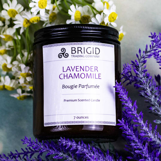 lavender chamomile bougie parfumee premium scented candle by brigid trading company soy wax hand poured hand made glass jar candle background is clouds with lavender and chamomile flowers and candle product photo in center