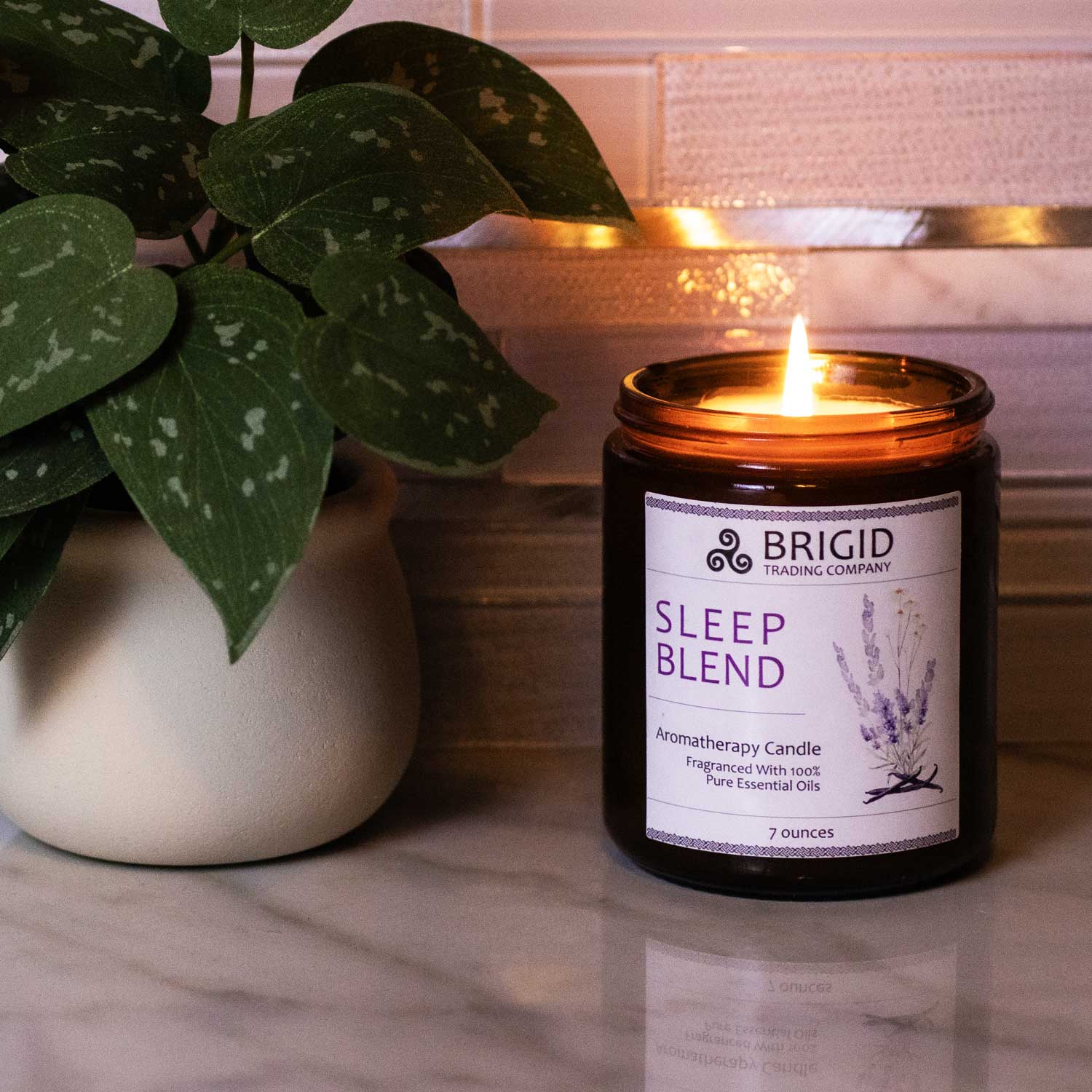 sleep blend aromatherapy candle by brigid trading company hand poured soy wax all natural boutique hand made candle dark amber glass shown on a marble countertop with glass tile backsplash light colored with green plant in a white pot by brigid trading company llc kitsap county washington state