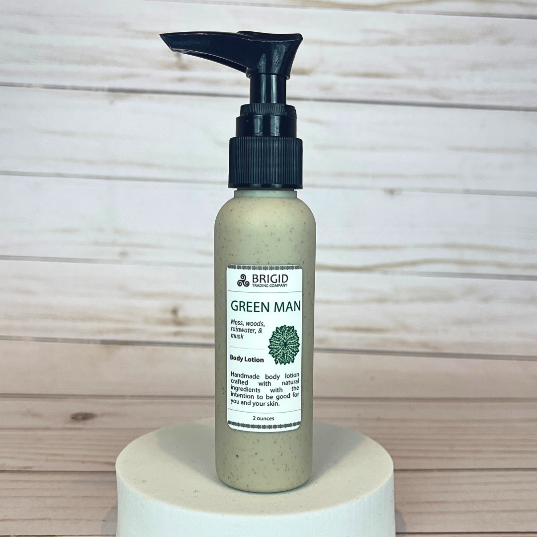 Bottle of Brigid Green Man body lotion on a wooden background green man body lotion 2 ounce bottle eco friendly packaging travel size tsa approved