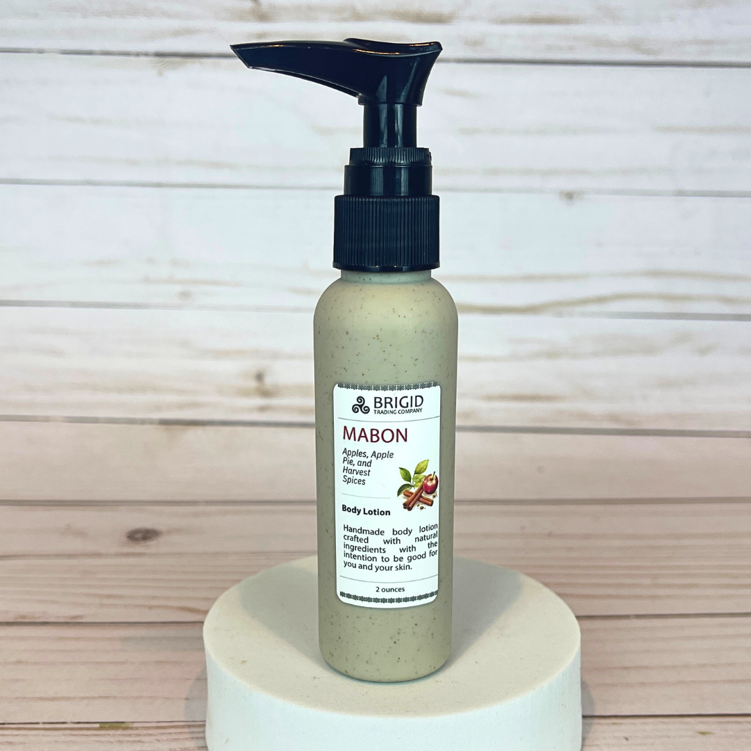 Body lotion bottle labeled 'MABON' by Brigid on a wooden background 2 ounce bottle wheat straw eco friendly pump bottle travel size tsa approved apple body lotion cinnamon fresh apples and apple pie