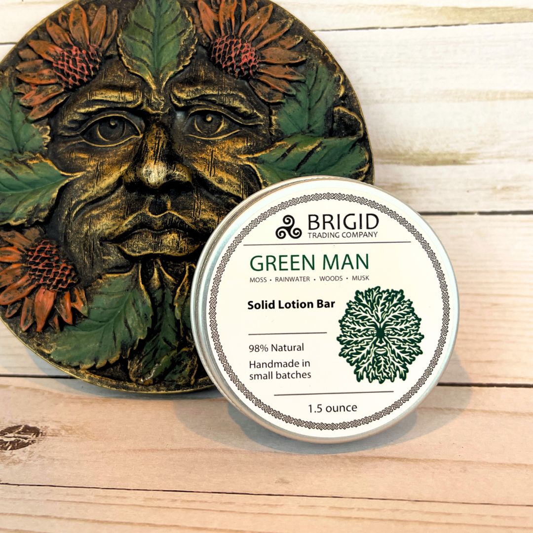 Solid lotion bar packaging with 'Green Man' design on a wooden surface green man solid lotion bar by brigid trading company beeswax shea butter and mango butter solid lotion bar natural ingredients raw oils olive sunflower jojoba almond handmade in small batches made in the usa manufactured in america washington state usa