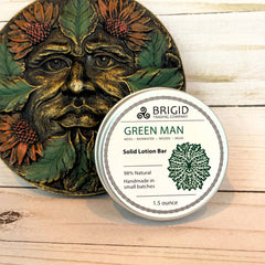 Solid lotion bar packaging with 'Green Man' design on a wooden surface green man solid lotion bar by brigid trading company beeswax shea butter and mango butter solid lotion bar natural ingredients raw oils olive sunflower jojoba almond handmade in small batches made in the usa manufactured in america washington state usa